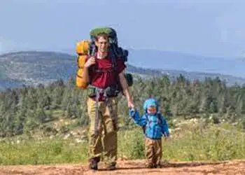 A man with a backpack holding his kid in his hand. Backpacking with Kids